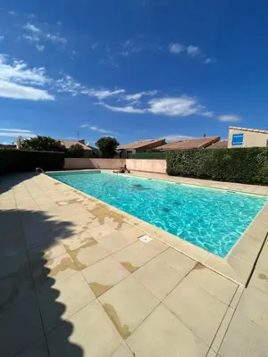 a swimming pool with blue water in a yard at La maisonnette de Gruissan in Gruissan