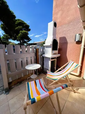 a chair and a table and a stove on a patio at La maisonnette de Gruissan in Gruissan