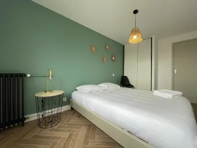 a bedroom with a bed and a black chair at Appartement cosy avec vue imprenable sur la cité in Carcassonne
