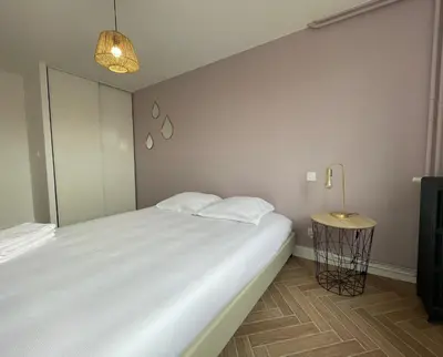 a bedroom with a large white bed and a lamp at Appartement cosy avec vue imprenable sur la cité in Carcassonne
