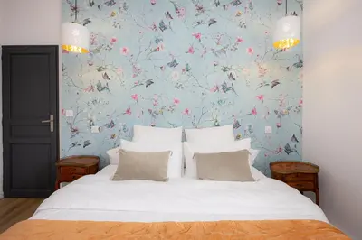 a bedroom with a large bed with a floral wallpaper at SalutBB Chambre d'hote in Carcassonne