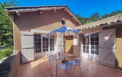 a patio with a table and an umbrella at Awesome Home In Ferrières-Poussarou in Ferrières-Poussarou
