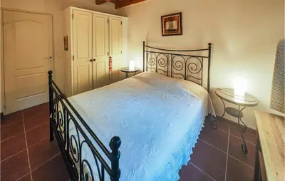 a bedroom with a bed with blue sheets and two tables at Awesome Home In Ferrières-Poussarou in Ferrières-Poussarou