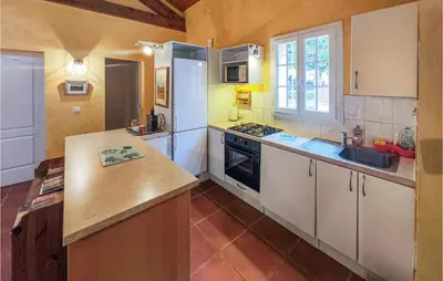 a kitchen with white cabinets and a counter top at Awesome Home In Ferrières-Poussarou in Ferrières-Poussarou