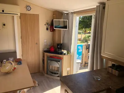 a small kitchen with a fireplace and a door to a yard at Cathy & David-Mobile Home 11-Camping Novela in Port-la-Nouvelle