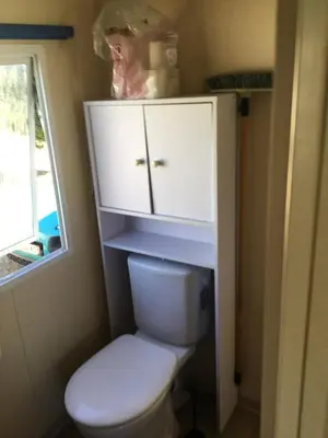 a bathroom with a toilet and a cabinet and a window at Cathy & David-Mobile Home 11-Camping Novela in Port-la-Nouvelle
