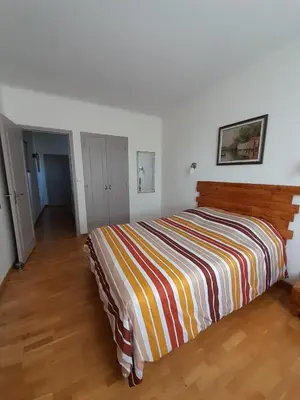 a bedroom with a bed with a colorful striped blanket at La pause sous le pin B&B Chambres d'hôtes in Capestang