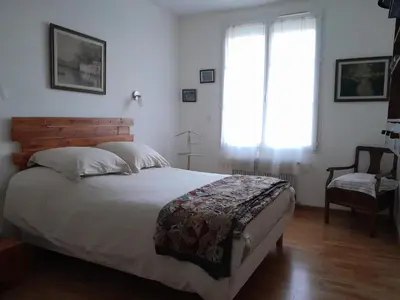 a bedroom with a bed and a window and a chair at La pause sous le pin B&B Chambres d'hôtes in Capestang