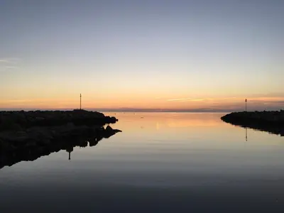 a body of water with a sunset in the background at Superbe appartement rénové avec vue magnifique in Gruissan