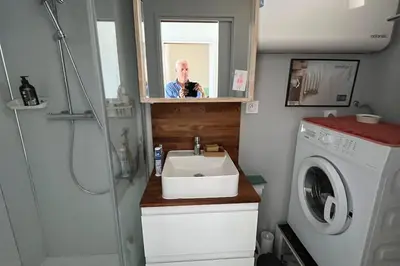 a man taking a picture of a bathroom with a sink at Superbe appartement rénové avec vue magnifique in Gruissan