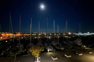 a view of a marina at night with a full moon at Superbe appartement rénové avec vue magnifique in Gruissan