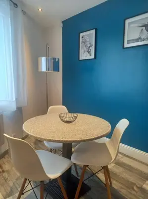 a table and chairs in a room with a blue wall at Cosy T2, Meublé de tourisme 3 étoiles, Parking fermé , 2Vélos, Wi-Fi in Narbonne
