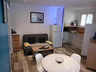 a living room with a table and a kitchen at Cosy T2, Meublé de tourisme 3 étoiles, Parking fermé , 2Vélos, Wi-Fi in Narbonne