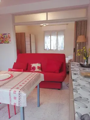 a red couch in a living room with a table at Chez Mi, centre ville, parking gratuit in Saint-Chinian
