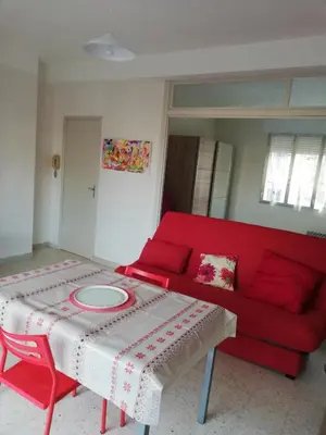a living room with a red couch and a table at Chez Mi, centre ville, parking gratuit in Saint-Chinian