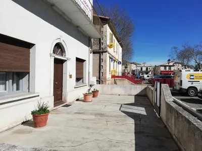 a sidewalk outside of a white building with potted plants at Chez Mi, centre ville, parking gratuit in Saint-Chinian