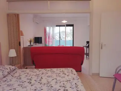 a bedroom with a red bed and a window at Chez Mi, centre ville, parking gratuit in Saint-Chinian