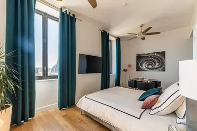 a bedroom with a bed with green curtains and a tv at The Gatsby room - 50m des halles - Design avec ascenseur in Narbonne