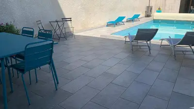 a patio with chairs and a table and a swimming pool at Logis de la Foulerie in Bize-Minervois