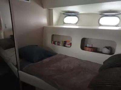 a small bedroom with a bed and two windows at Loc de cabines sur Yacht in Gruissan