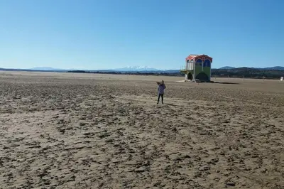 a person standing on a beach flying a kite at Studio Plage 200m Parking gratuit Port la Nouvelle in Port-la-Nouvelle