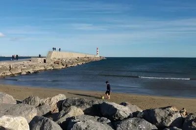 a person walking on the beach near the ocean at Studio Plage 200m Parking gratuit Port la Nouvelle in Port-la-Nouvelle