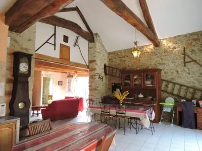 a living room with a table and chairs in a building at Gîte LA FENIAL in Montredon-Labessonnié