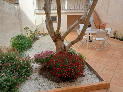 a tree in a garden with flowers and a table at Le Patio in Villegailhenc