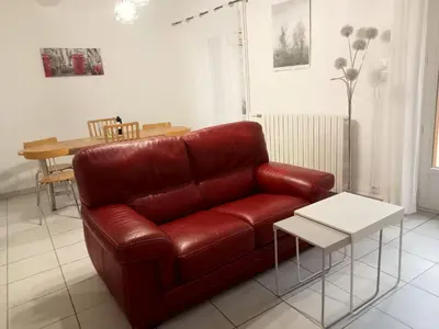 a red leather couch in a living room with a table at Le Patio in Villegailhenc