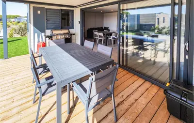 a wooden deck with a table and chairs on a house at Gorgeous Home In Olonzac With Kitchen in Olonzac