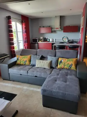 a living room with a couch and a kitchen at La Bastide du Canal avec piscine et clim in Carcassonne