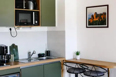 a kitchen with a sink and two bar stools at Studio avec parking vue sur la Cité de Carcassonne in Carcassonne