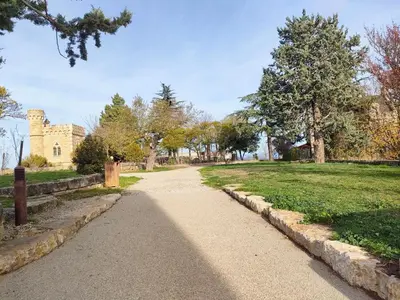 a path in a park with a building in the background at Gîte chaleureux au cœur du village in Roquetaillade