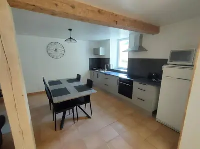 a kitchen with a table and a dining room at Gîte chaleureux au cœur du village in Roquetaillade
