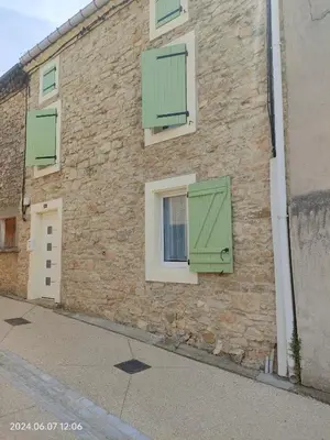 a brick building with green shutters on it at Gîte chaleureux au cœur du village in Roquetaillade