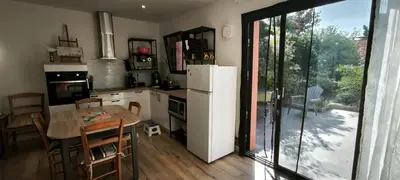 a kitchen with a table and a white refrigerator at L'Annexe in Sigean