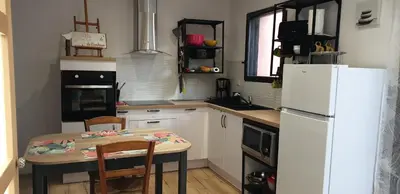 a kitchen with a table and a white refrigerator at L'Annexe in Sigean