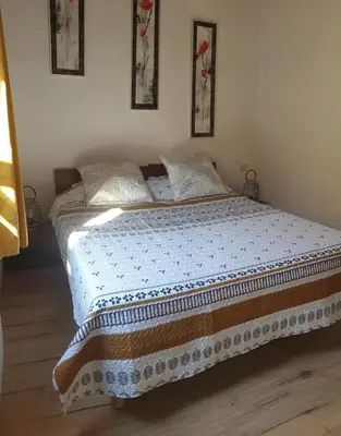 a bedroom with a bed with a blue and white blanket at L'Annexe in Sigean