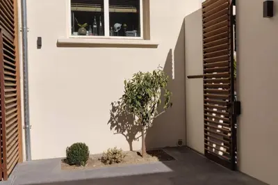 a house with a tree in a courtyard next to a door at La Maison de Colette - Coeur de village in Cuxac-dʼAude