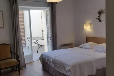 a bedroom with a bed and a chair and a balcony at La Maison de Colette - Coeur de village in Cuxac-dʼAude