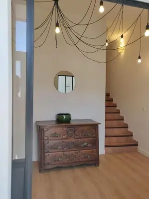 a room with a dresser and a staircase with a mirror at La Maison de Colette - Coeur de village in Cuxac-dʼAude