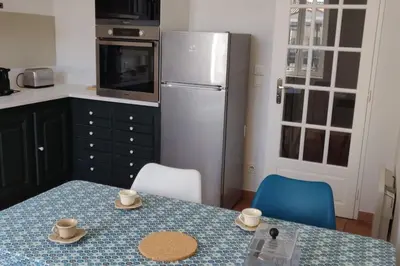 a kitchen with a table with two chairs and a refrigerator at La Maison de Colette - Coeur de village in Cuxac-dʼAude