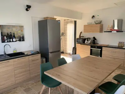 a kitchen with a wooden table and a refrigerator at Villa 18 in Narbonne