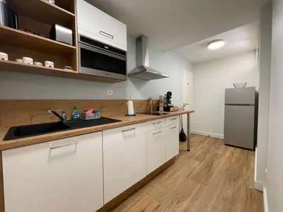 a kitchen with white cabinets and a stainless steel refrigerator at Au point du jour - Gîtes Carcassonne, Lac de la Cavayère in Carcassonne