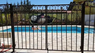 a gate with a panda bear laying next to a pool at Tranquillité Gite in Cuxac-dʼAude