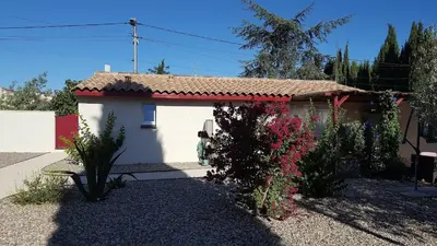 a small white house with flowers in front of it at Tranquillité Gite in Cuxac-dʼAude