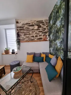 a living room with a couch and a stone wall at LE GITE SPA DU CEDRE BLEU in La Tourette-Cabardès