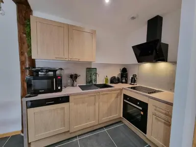 a kitchen with wooden cabinets and a black microwave at LE GITE SPA DU CEDRE BLEU in La Tourette-Cabardès