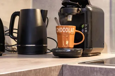 a coffee cup sitting on a counter next to a coffee maker at LE GITE SPA DU CEDRE BLEU in La Tourette-Cabardès