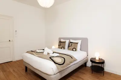 a bedroom with a bed with white walls and wood floors at La Pittoresque 1 in Carcassonne